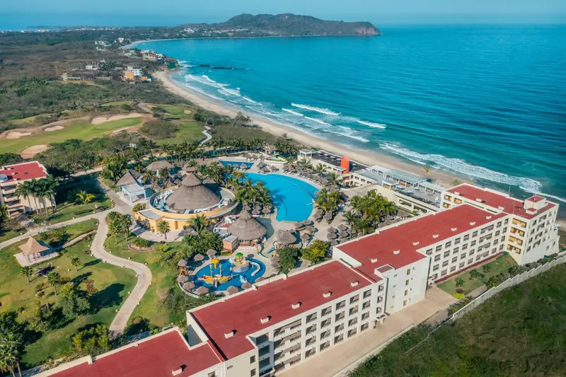 Vue aérienne d'un complexe hôtelier avec piscine et plage.