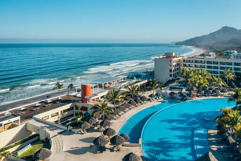 Vue aérienne d'un complexe hôtelier avec piscine et accès à la plage.