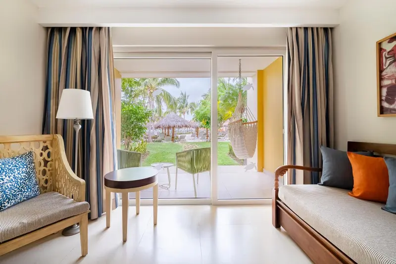 Espace de détente intérieur avec canapés et vue sur un jardin tropical.