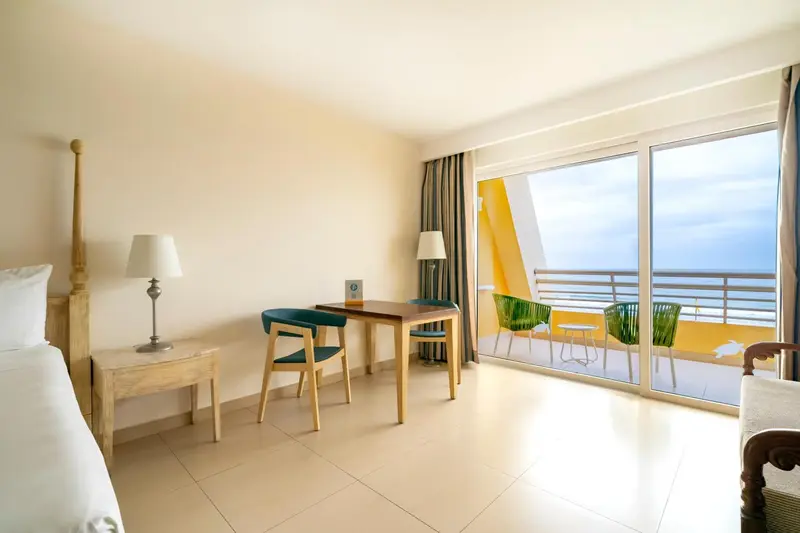 Une chambre lumineuse avec un bureau et un accès à un balcon.