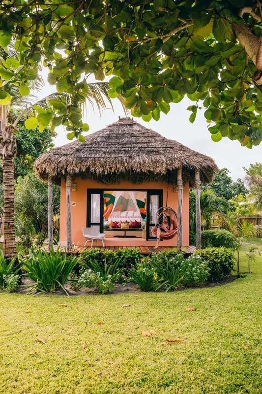 Petit pavillon de plage à toit de chaume avec mobilier de détente.