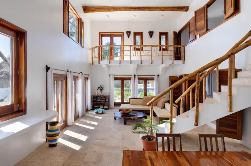 Espace de vie intérieur lumineux avec mezzanine et escalier en bois.
