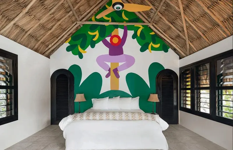 Une chambre lumineuse avec un grand lit et une décoration murale colorée.