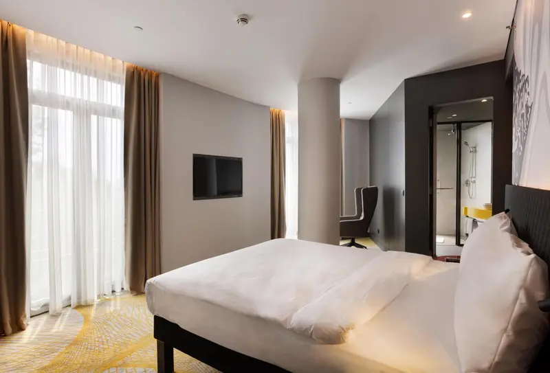 Chambre lumineuse avec un grand lit et un accès à la salle de bain.