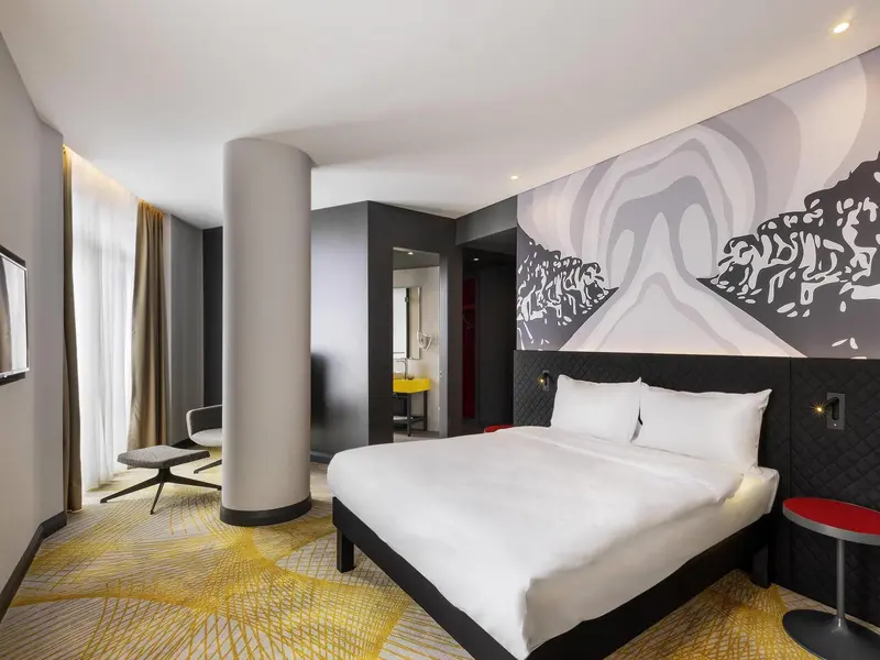 Chambre moderne avec un grand lit et un mur décoratif.