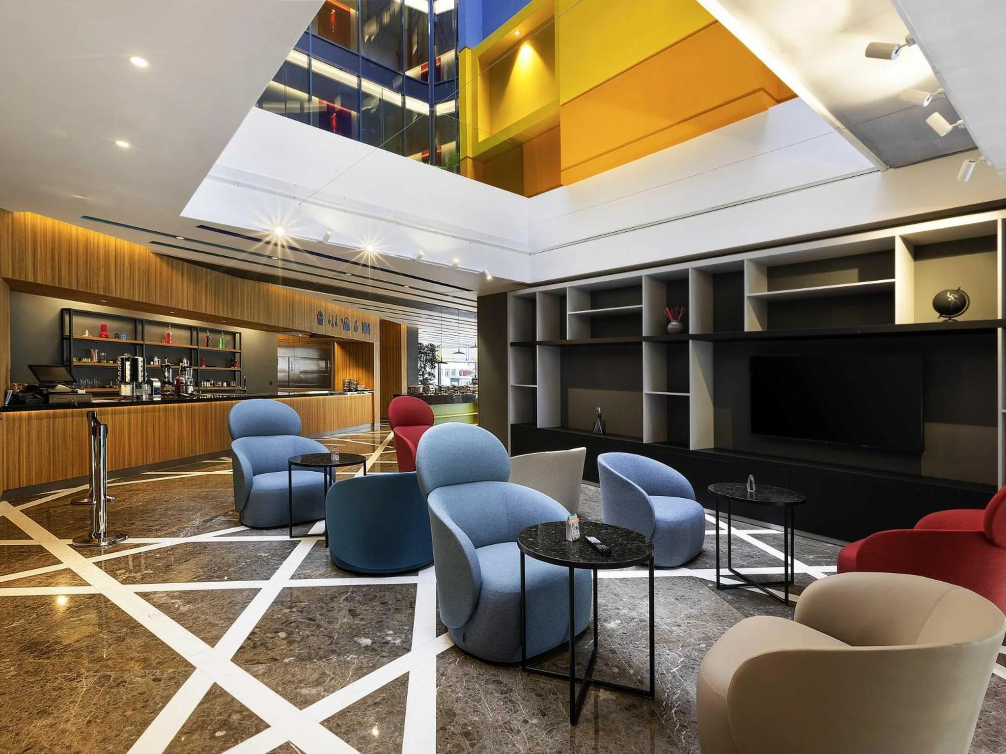 Un espace de détente intérieur avec des fauteuils colorés et un comptoir de boissons.