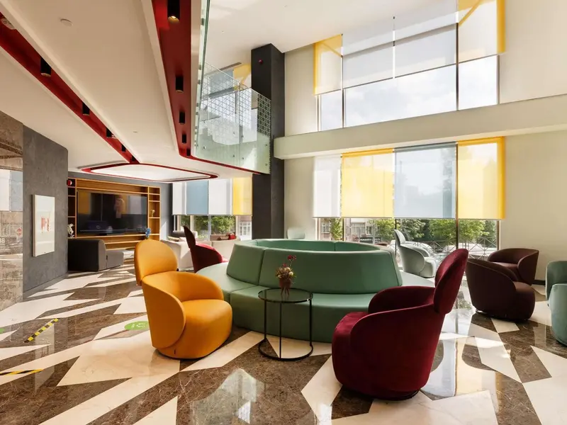 Un espace de détente intérieur avec des fauteuils colorés et un canapé circulaire.
