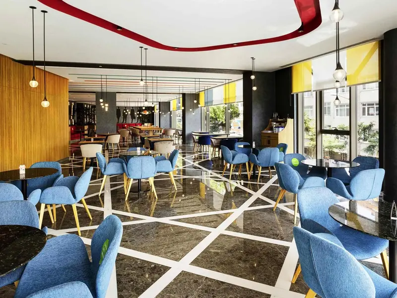 Une salle lumineuse avec des tables et des chaises colorées.