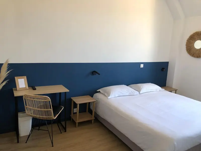 Une chambre lumineuse avec un lit blanc et un bureau en bois.