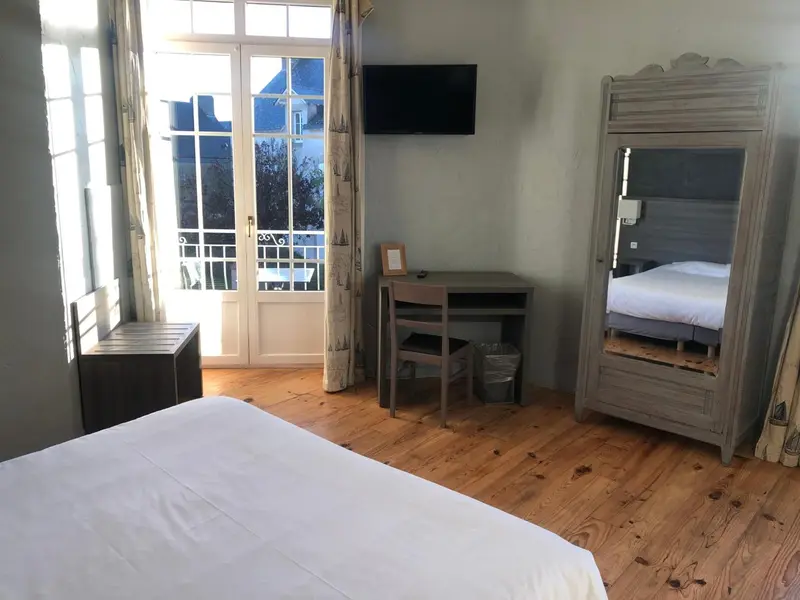 Une chambre lumineuse avec un lit et un bureau près d'une fenêtre.
