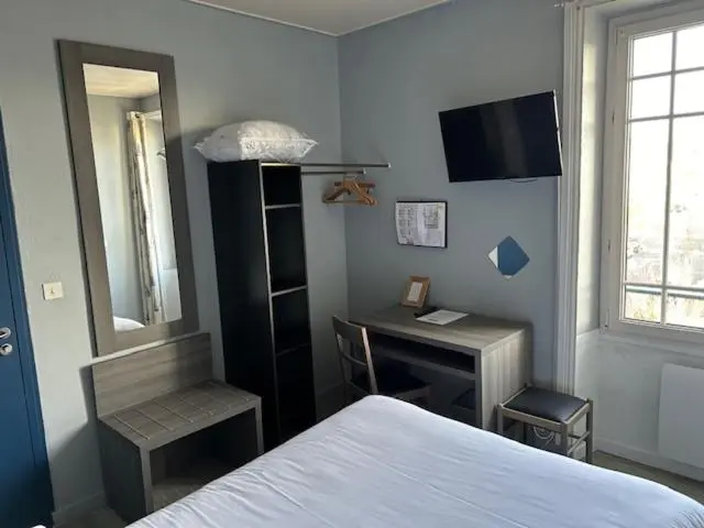 Une chambre lumineuse avec un lit, un bureau et un miroir.