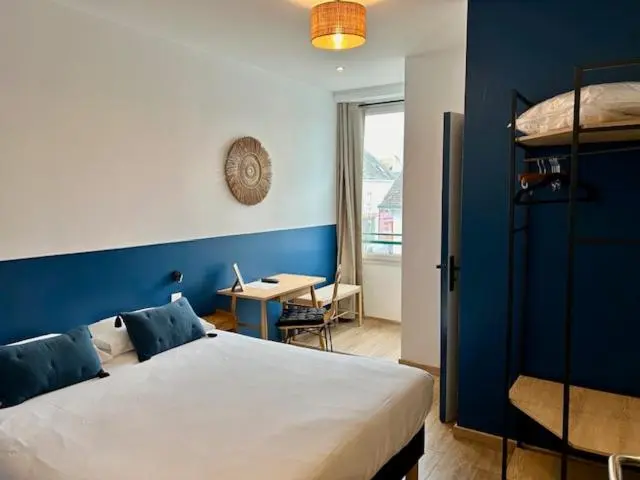 Une chambre lumineuse avec un lit et un bureau près d'une fenêtre.