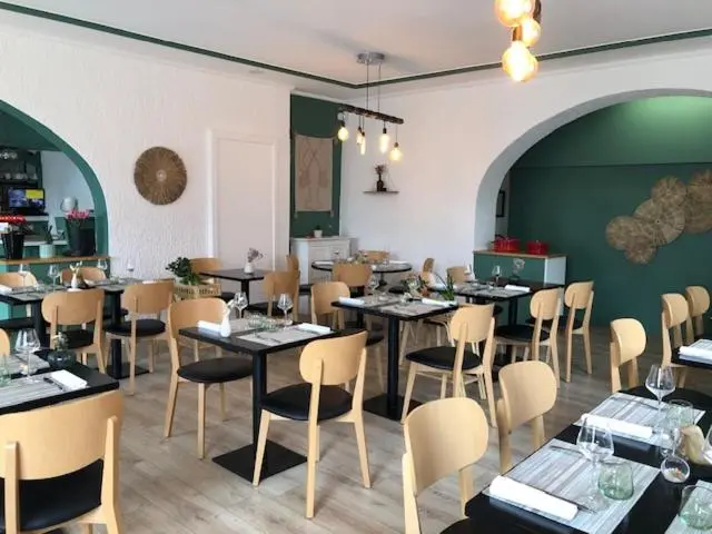 Une salle de restaurant lumineuse avec des tables dressées et des chaises en bois.