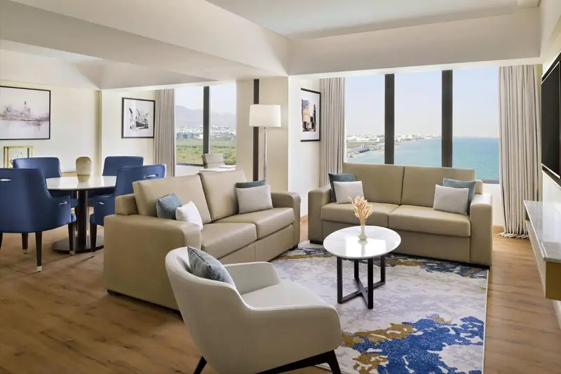Espace de vie lumineux avec canapés, fauteuils et table basse, donnant sur une vue mer.