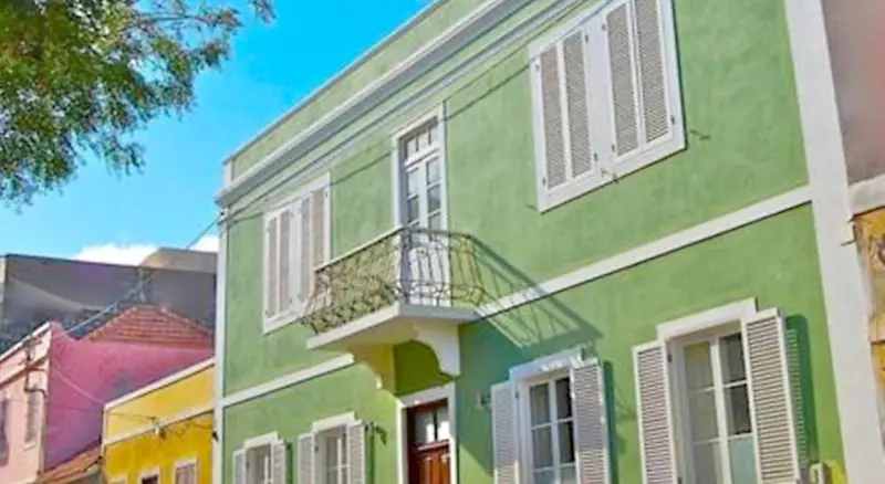 Façade d'un bâtiment vert à deux étages avec des fenêtres et un balcon.