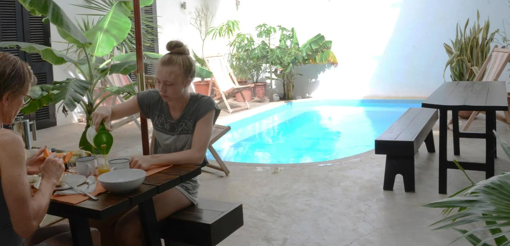 Des convives prennent leur petit-déjeuner à une table près d'une piscine.