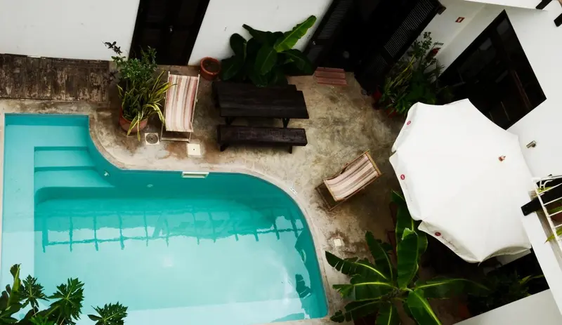 Espace piscine avec mobilier de jardin et végétation luxuriante.
