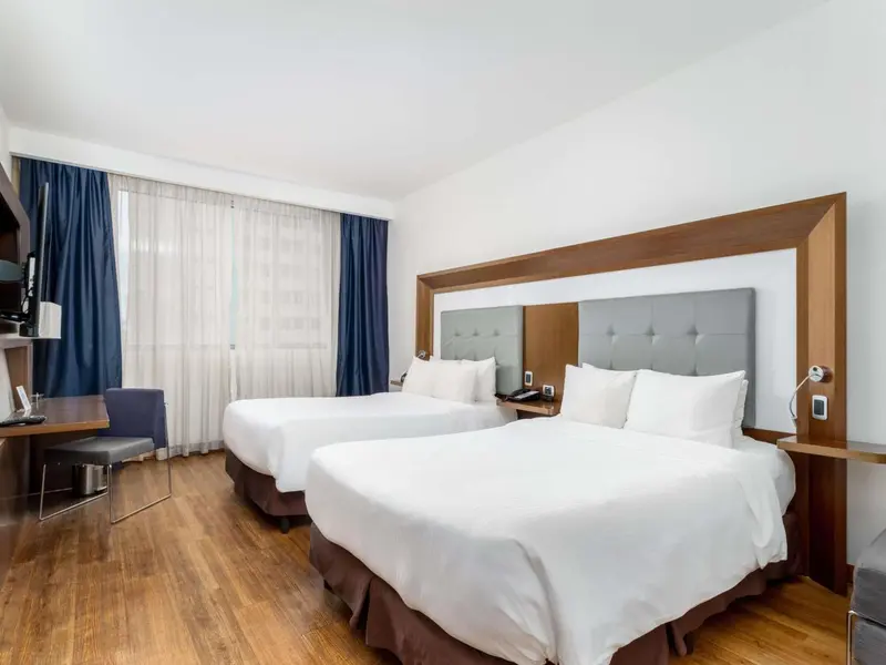 Une chambre d'hôtel avec deux lits jumeaux et un bureau.