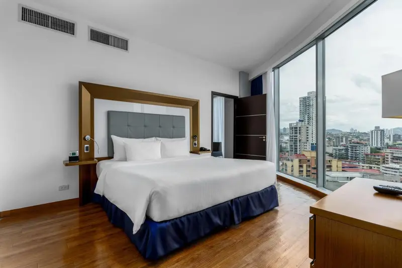 Une chambre lumineuse avec un grand lit et une vue sur la ville.