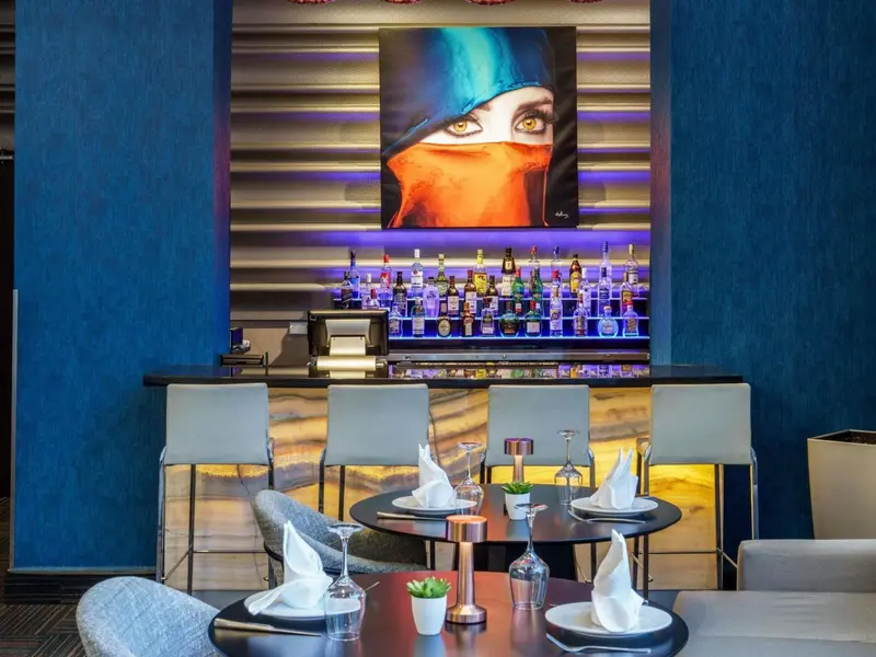 Un comptoir de bar moderne avec des tabourets et des tables préparées pour le service.