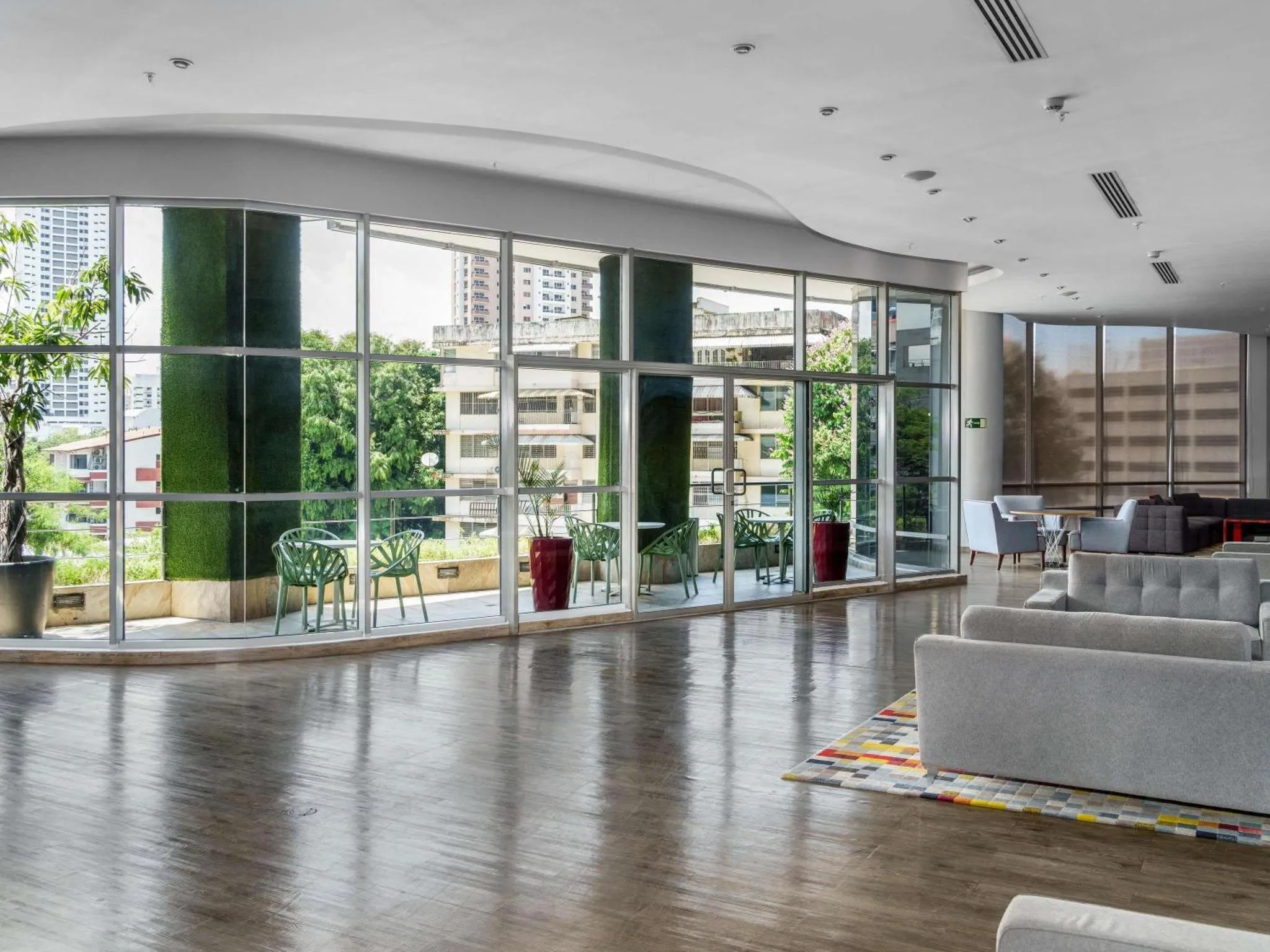 Espace de détente intérieur avec canapés et larges baies vitrées donnant sur une terrasse.