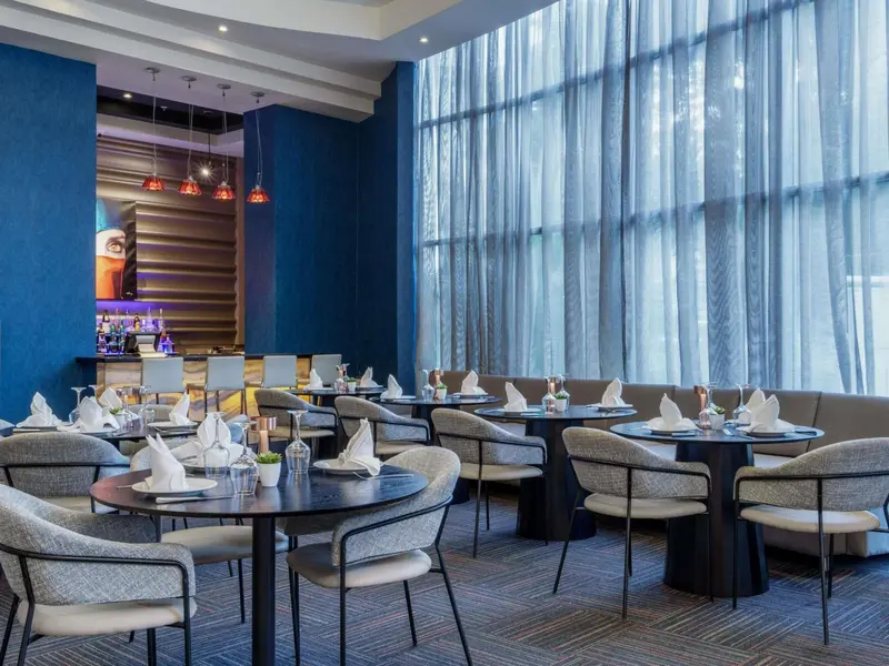 Une salle de restaurant lumineuse avec des tables dressées et des chaises.