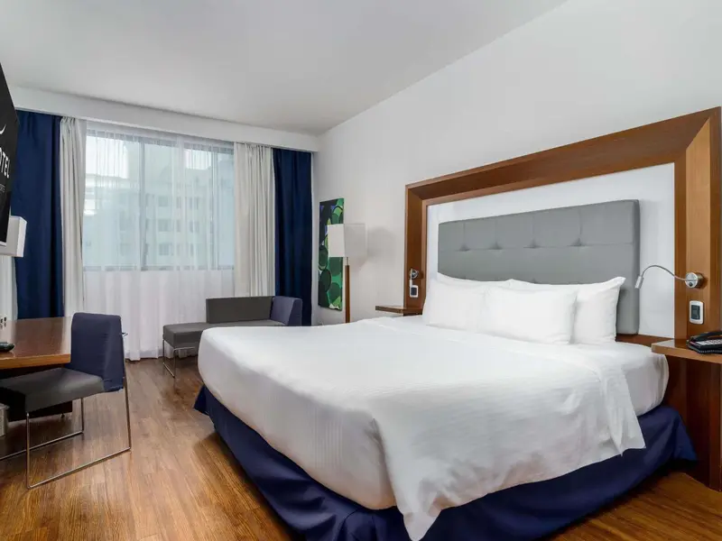 Une chambre d'hôtel lumineuse avec un grand lit et un bureau.