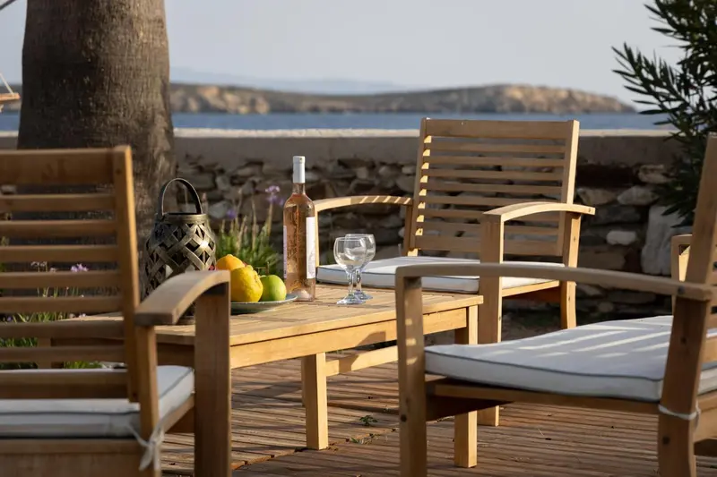 Une table en bois avec des chaises et des coussins sur une terrasse ensoleillée.