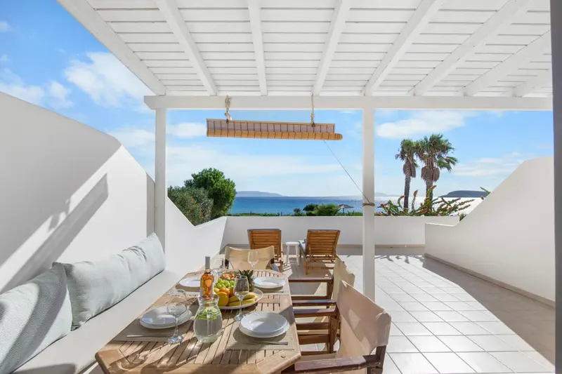 Table dressée sur une terrasse ombragée avec vue sur la mer.