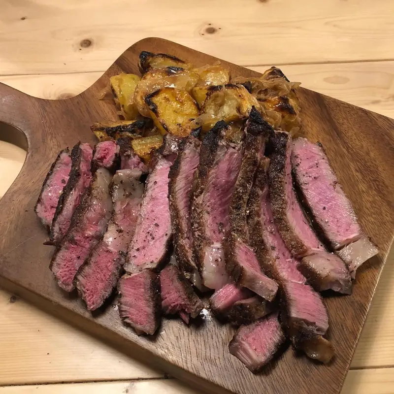 Une portion de viande grillée coupée en tranches est présentée sur une planche en bois.