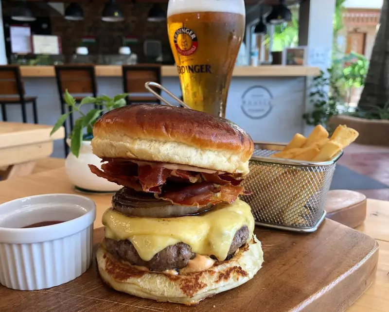 Un gros hamburger garni, accompagné de frites et d'une bière fraîche.