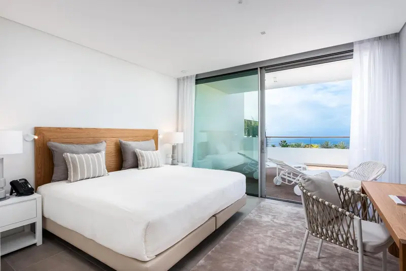 Chambre lumineuse avec un grand lit et une vue sur la mer.