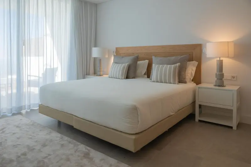 Une chambre lumineuse avec un grand lit et des tables de chevet.