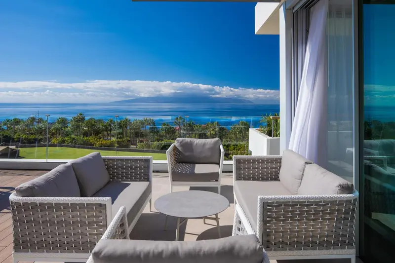 Terrasse aménagée avec salon et vue sur la mer et la végétation.