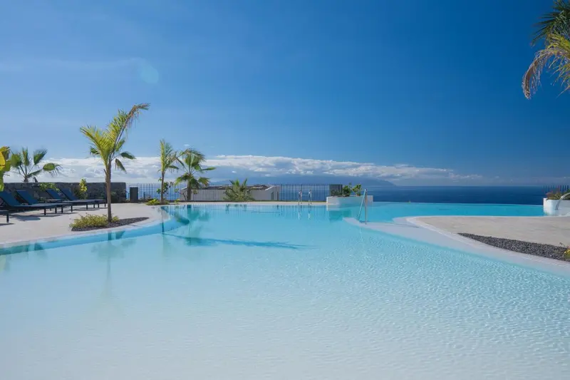 Piscine à débordement avec vue sur l'océan et le ciel bleu.