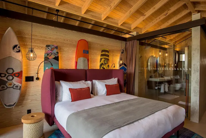 Une chambre à coucher avec un lit recouvert d'une couverture grise et de coussins rouges.