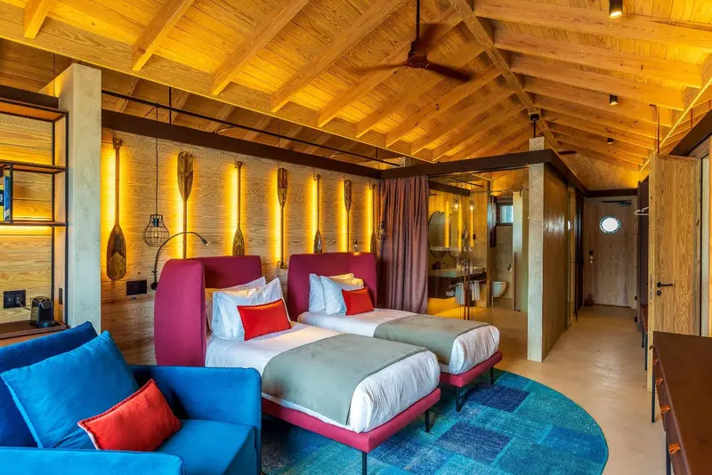 Chambre lumineuse avec deux lits simples et un coin salon.
