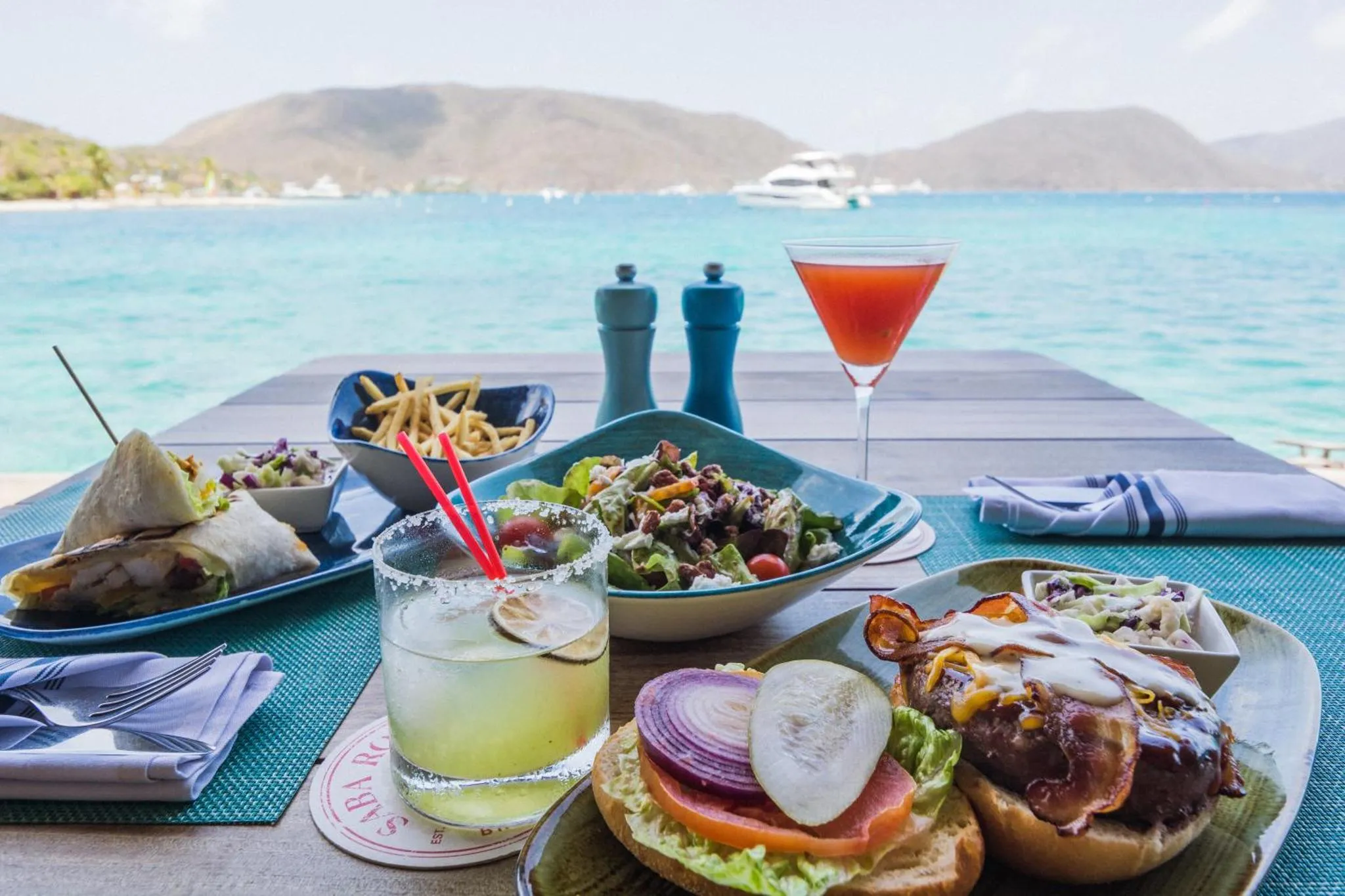 Une table est dressée avec des plats et des boissons en bord de mer.