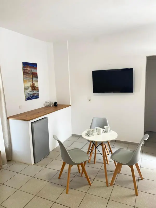 Une petite table ronde avec des chaises est placée devant un comptoir avec un réfrigérateur.