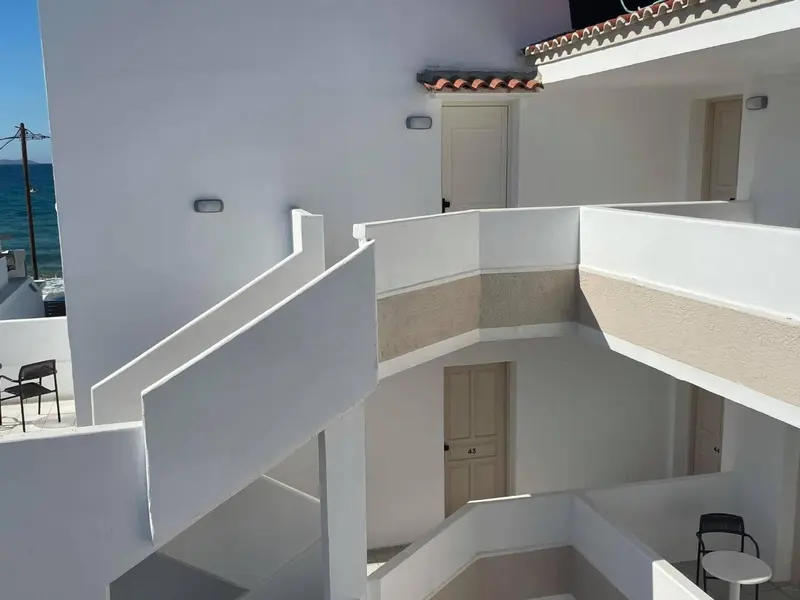 Architecture blanche avec des balcons et des escaliers menant à des portes.