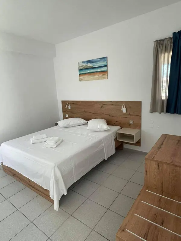 Une chambre lumineuse avec un grand lit blanc et une décoration murale marine.