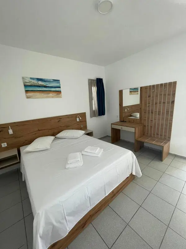 Une chambre lumineuse avec un grand lit et un coin coiffeuse en bois.