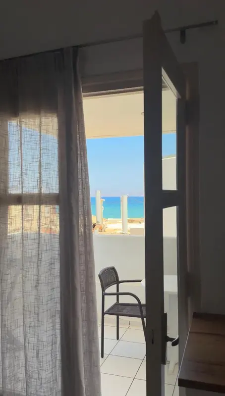 Une porte ouverte laisse voir une vue sur la mer et une terrasse.