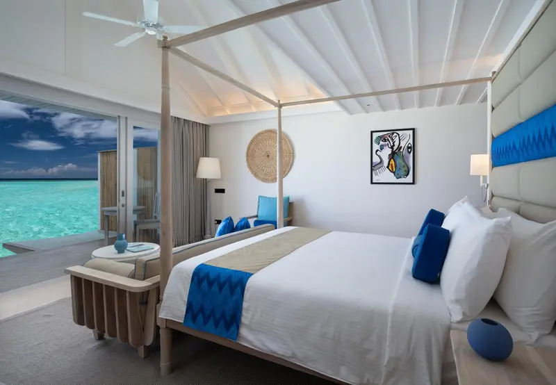 Une chambre lumineuse avec un lit à baldaquin donnant sur l'océan.