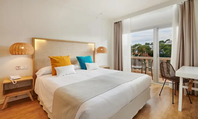 Une chambre lumineuse avec un grand lit et un balcon.