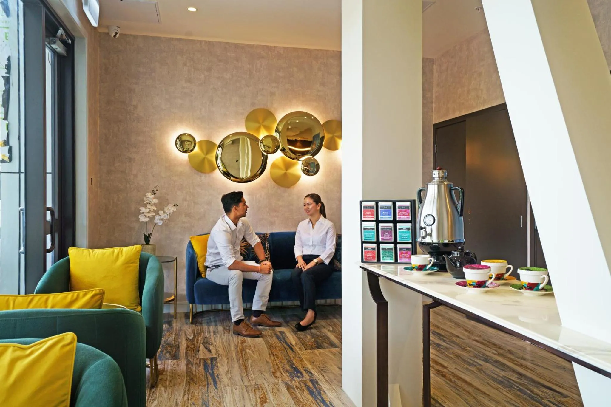 Un couple discute confortablement dans un espace de détente avec un canapé et un comptoir de boissons.