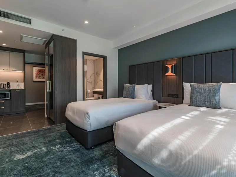 Une chambre avec deux lits simples et un coin cuisine.