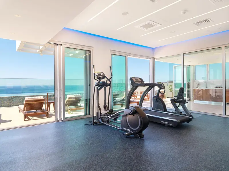 Une salle de sport lumineuse donne sur une terrasse avec vue sur la mer.