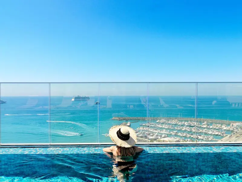 Une personne contemple la mer depuis une piscine à débordement.