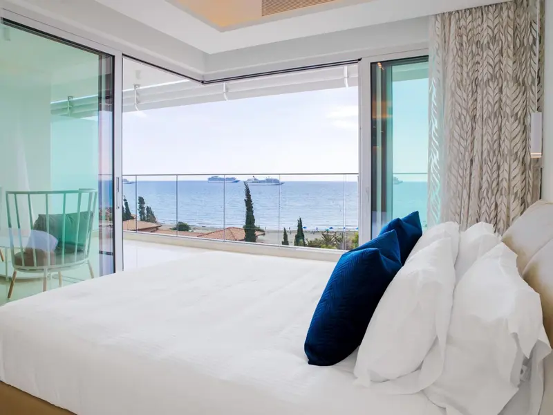 Une chambre lumineuse avec un grand balcon donnant sur la mer.